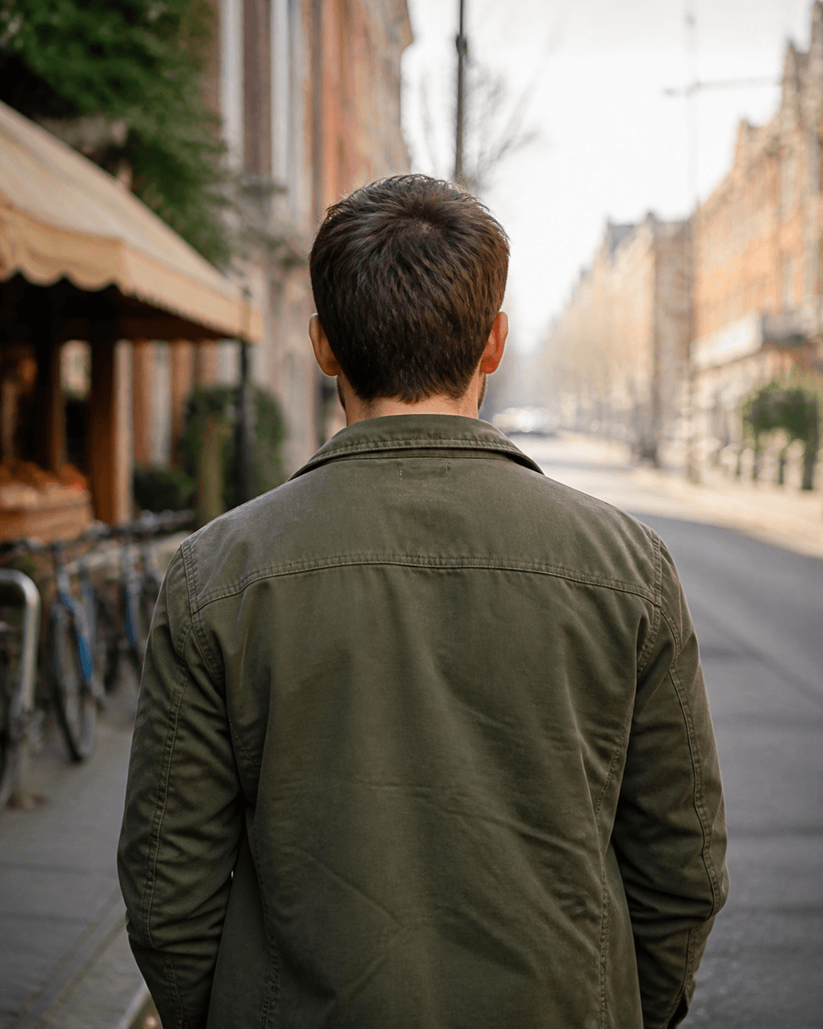 Mann von hinten auf einer Stadtstraße, Blick die Straße hinunter, sein Gesicht ist nicht im Bild
