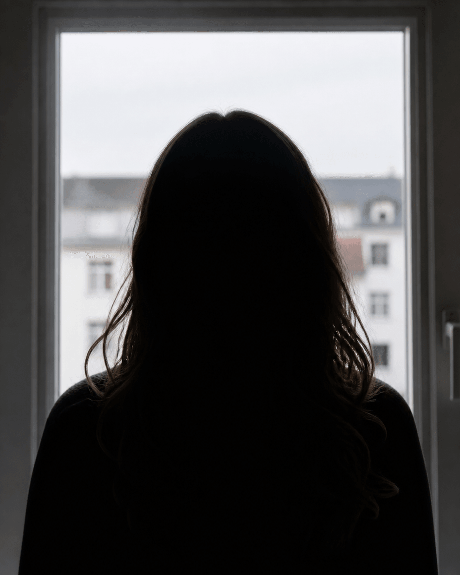 Junge Frau als dunkler Umriss vor einem hellen Fenster, Haar und Schultern scharf gezeichnet, das Gesicht ohne Details