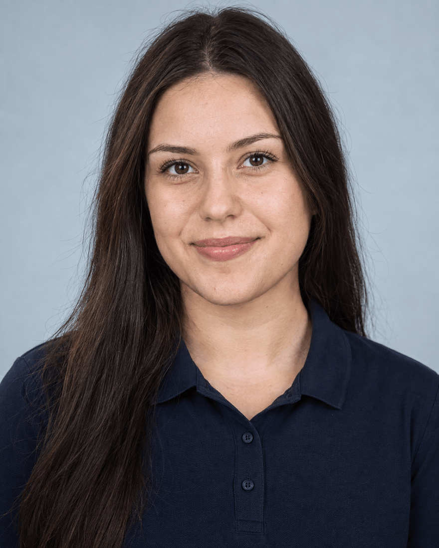 Junge Frau um 19 mit offenem dunklem Haar im dunkelblauen Poloshirt vor hellblau-grauem Hintergrund, Bewerbungsfoto für eine Ausbildung in der Dortmunder Industrie