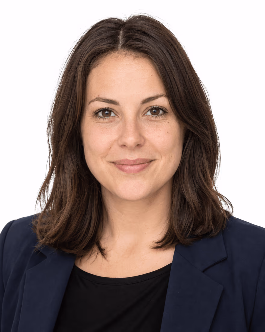 Ritratto di una donna con blazer blu scuro su sfondo bianco uniforme, ripresa dal busto in su