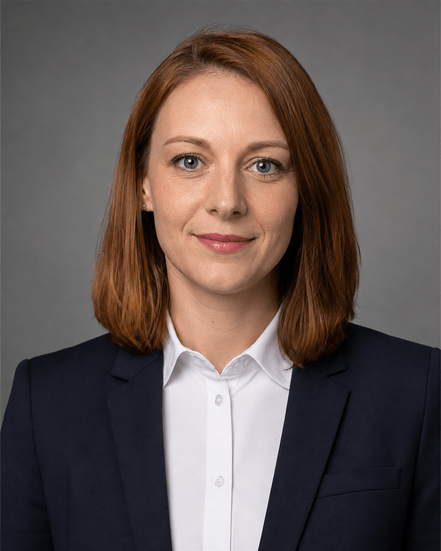 Frau Anfang dreißig mit rotbraunem Haar in frisch gebügeltem weißem Hemd unter offenem dunkelblauem Blazer