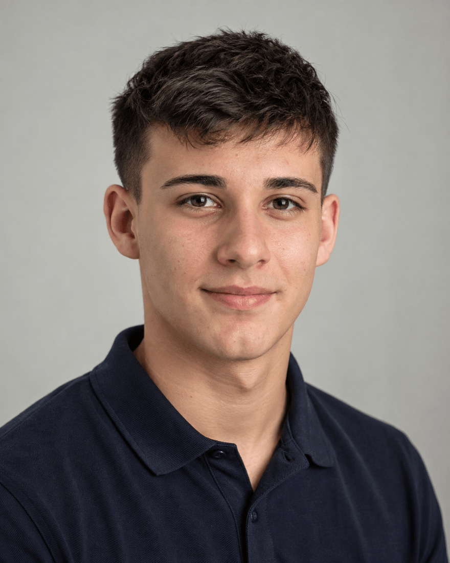 Bewerbungsfoto eines etwa achtzehnjährigen jungen Mannes mit kurzen dunklen Haaren in dunkelblauem Poloshirt vor hellgrauem Hintergrund