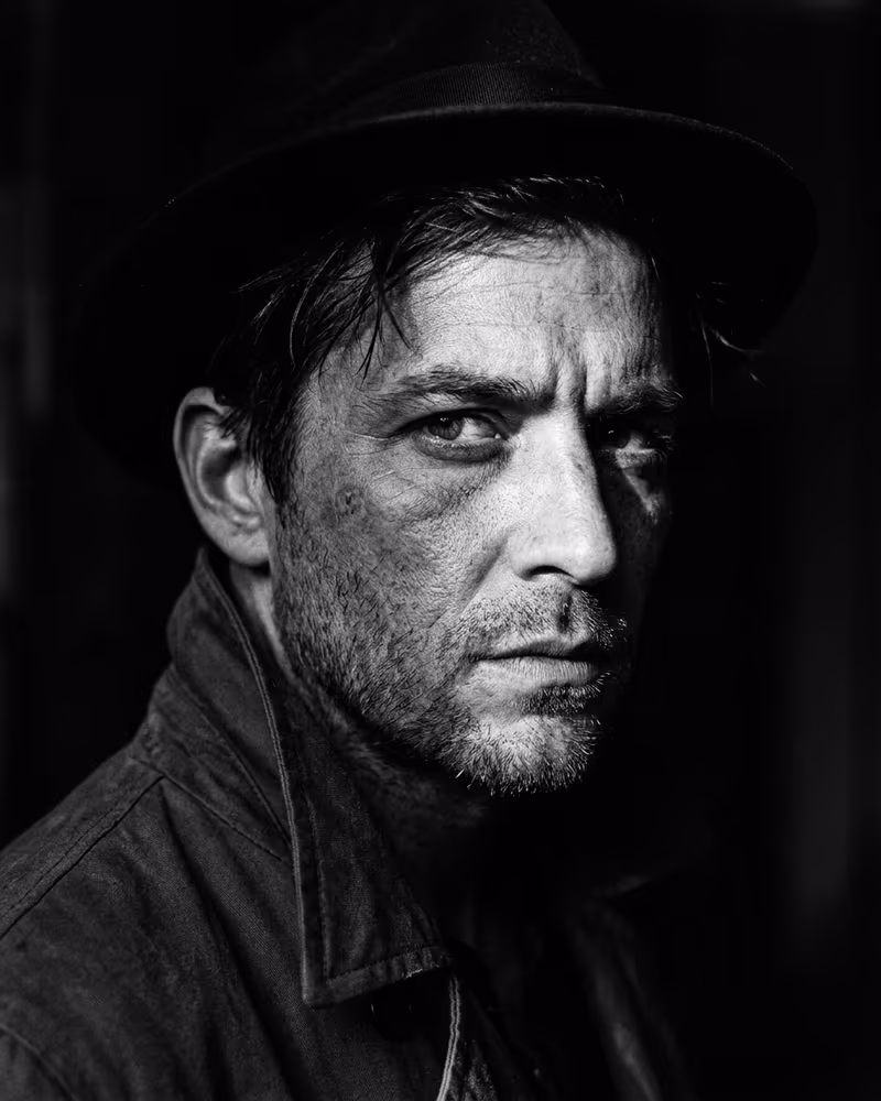 Schwarz-Weiß-Profilbild im Noir-Stil: hartes Seitenlicht und tiefe Schatten