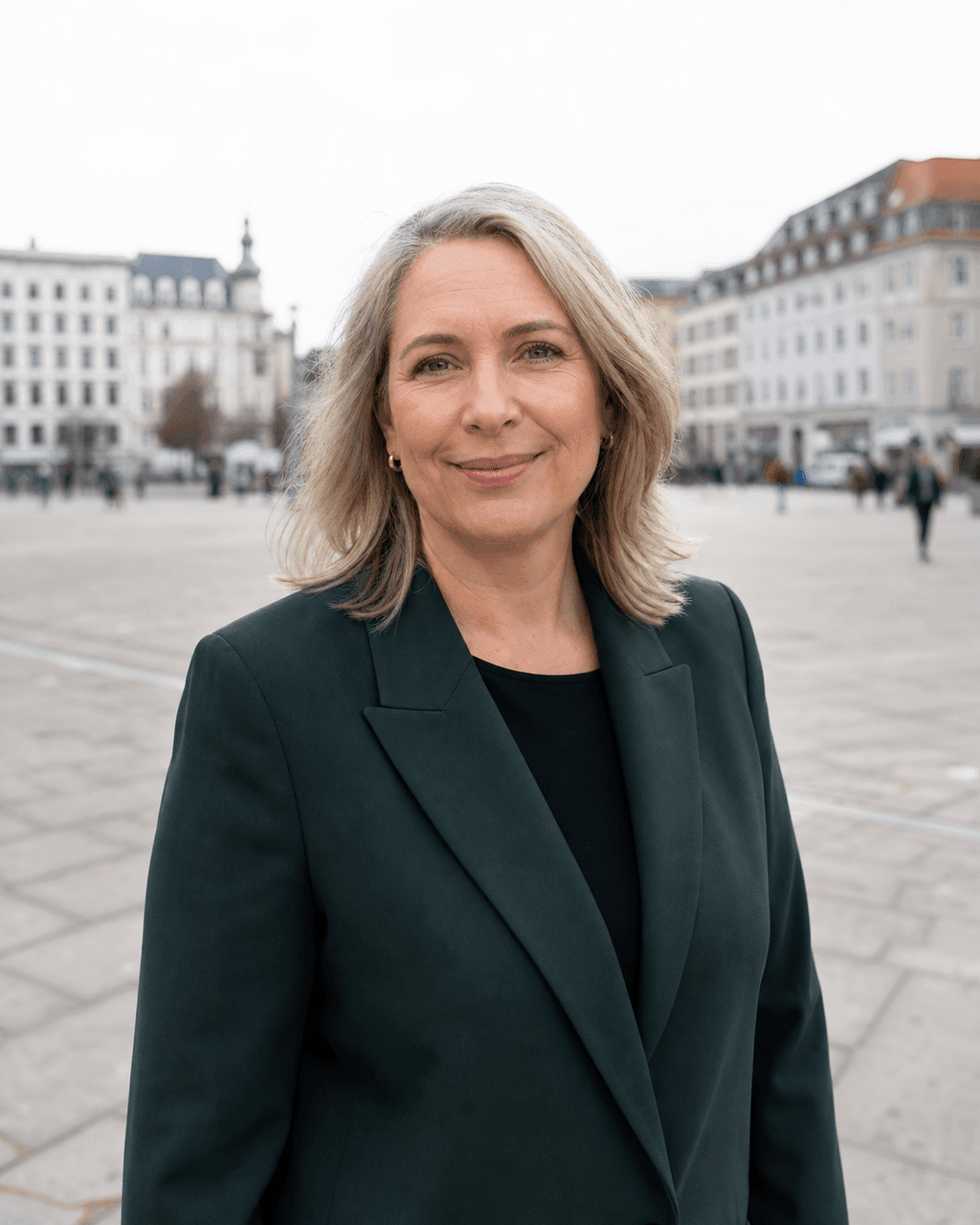 Frau Mitte vierzig auf einem offenen Platz bei geschlossener Wolkendecke, das Licht flach und schattenfrei im Gesicht