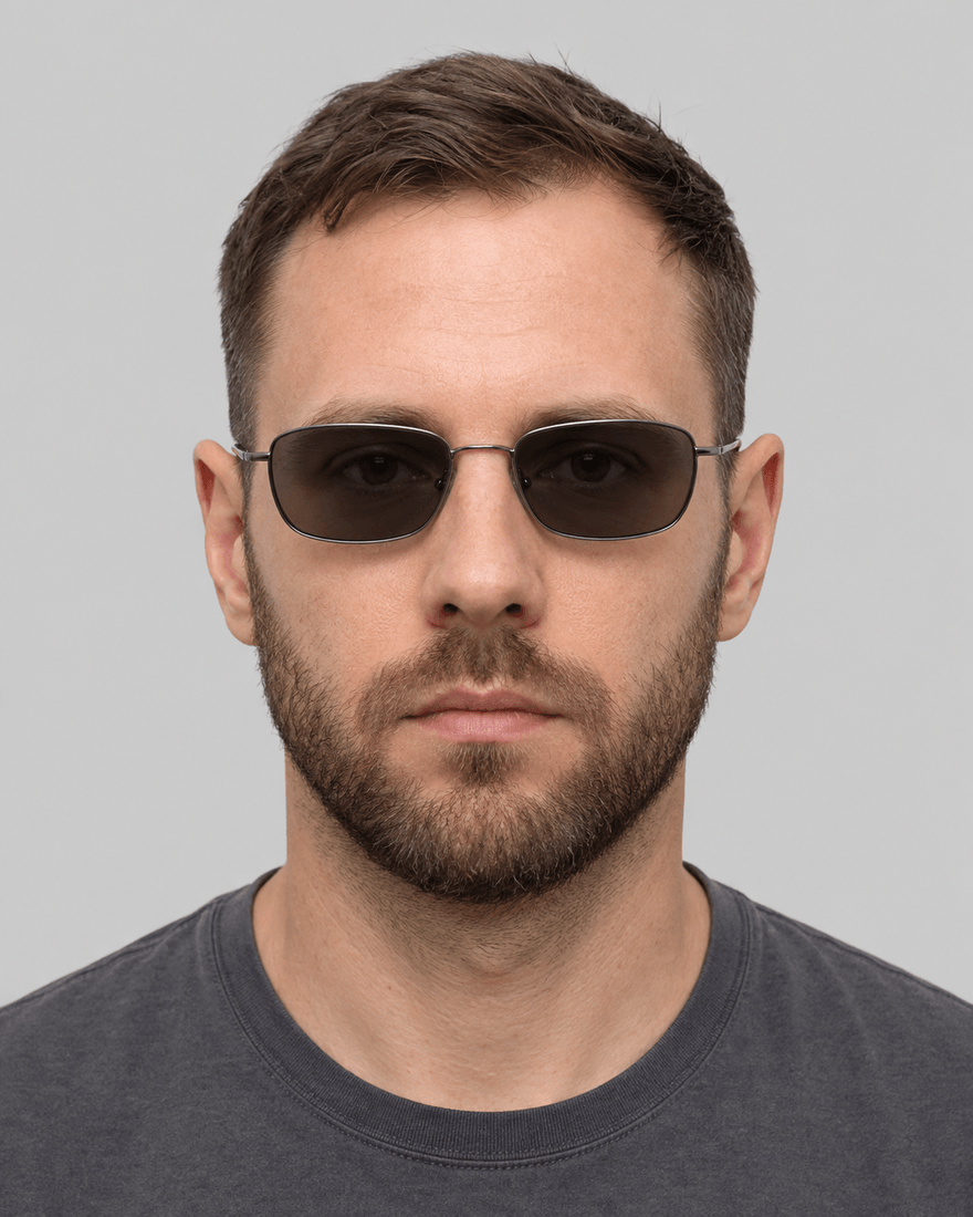 Mann Mitte dreißig mit dünnem Gestell und deutlich braungrau getönten Gläsern, die Augen liegen hinter dem Glas im Schatten