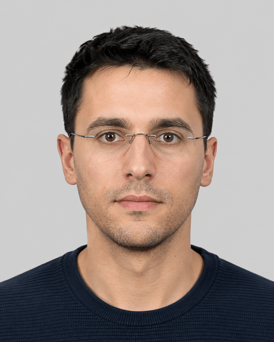 Mann Ende zwanzig mit sehr dünner randloser Brille vor hellgrauem Grund, die Gläser sind klar und beide Pupillen vollständig zu sehen